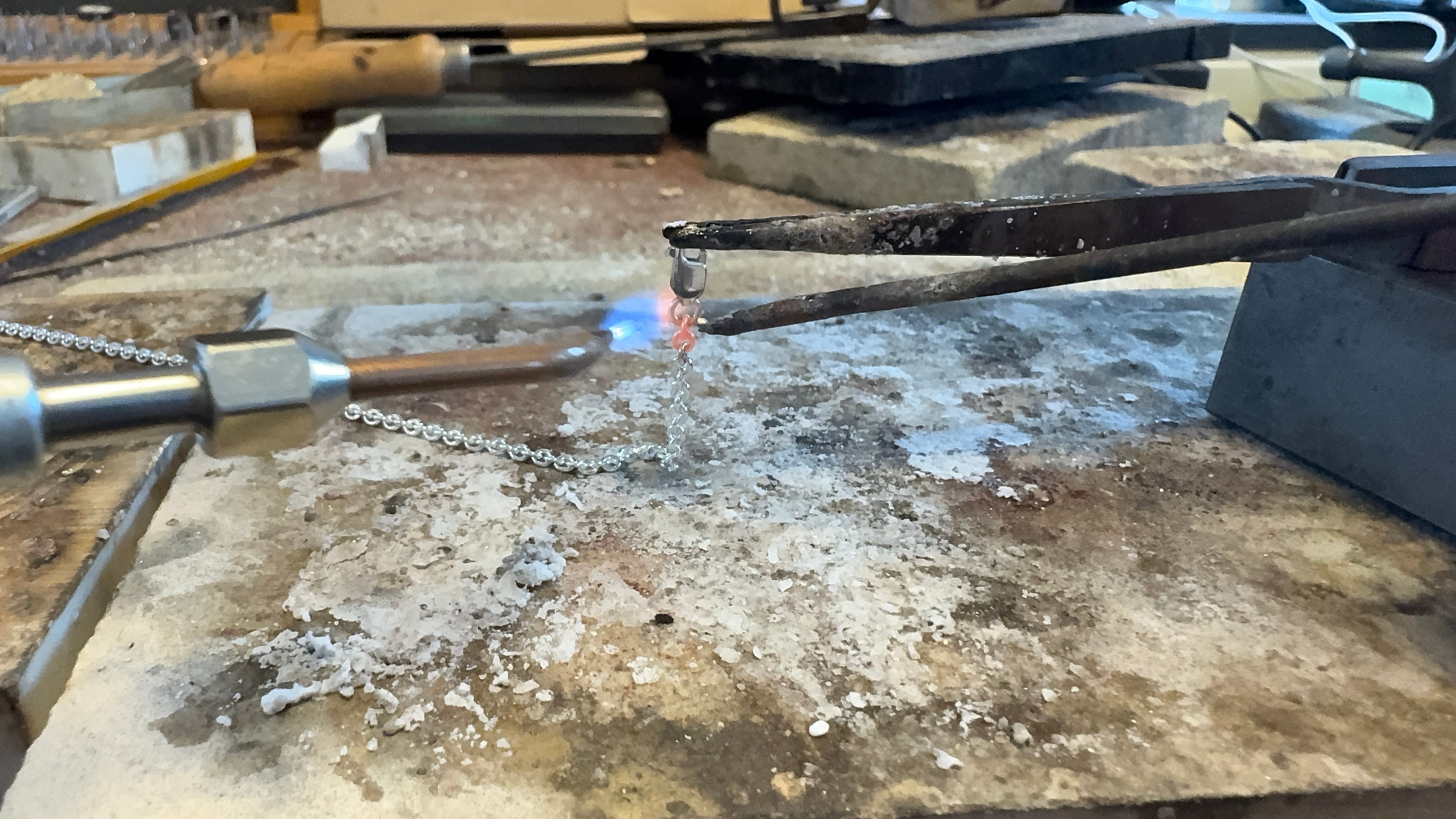 Goudsmid van Atelier Per Sempre soldeert een zilveren ketting tijdens een sieradenreparatie in het atelier in Zoetermeer.