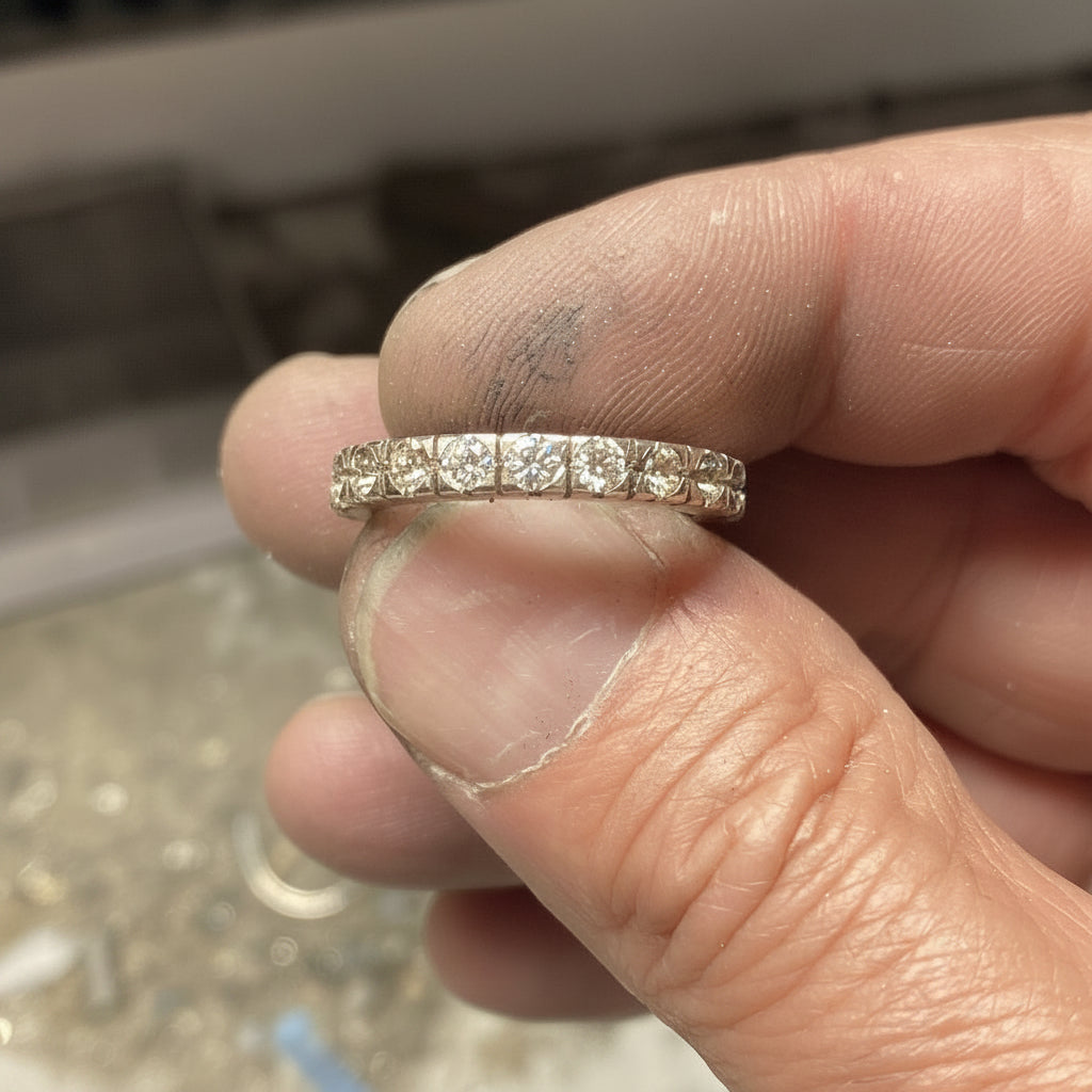 Goudsmid zet diamanten in een alliance ring met de hand in atelier in Zoetermeer