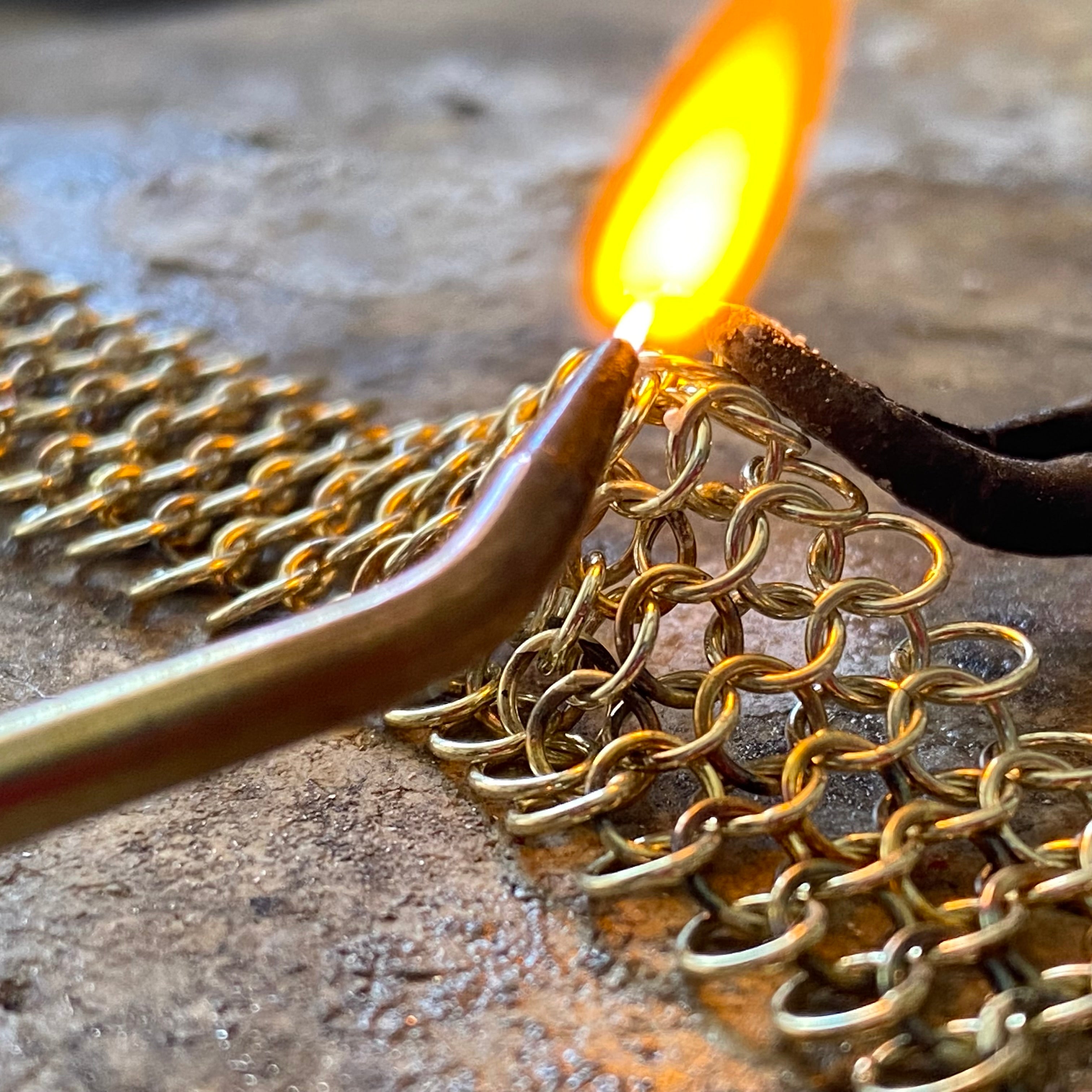 Goudsmid soldeert een gouden ketting in het atelier in Zoetermeer
